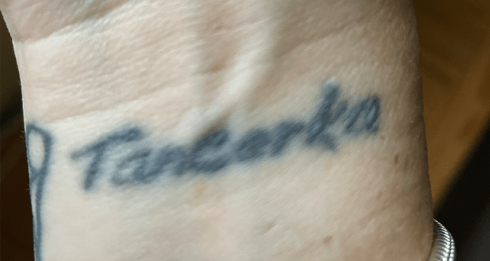 [J Bee is a female in her forties with a tattoo of the Polish word for “dancer” on her wrist]