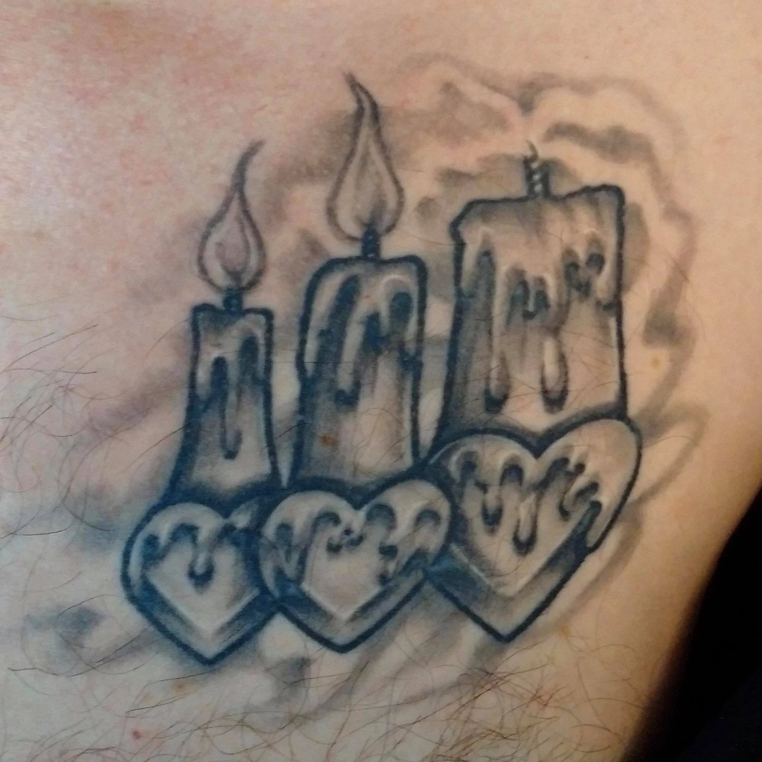 Tattoo of three candles and hearts.