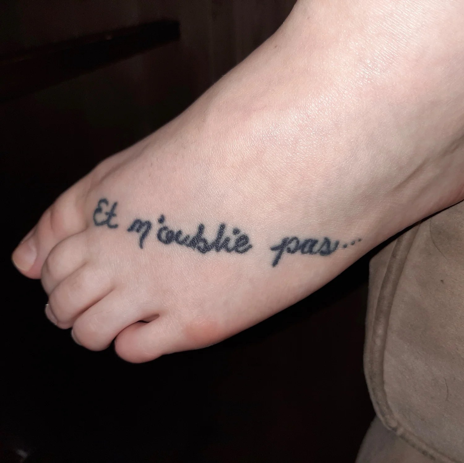 Tattoo of the words and don’t forget in French on a foot.